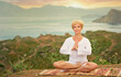 © luengo_ua - Senior woman doing yoga exercises with mountain on the background