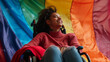 Close-up of a dark-skinned girl's infectious smile as she sits confidently in a wheelchair, the colorful stripes of an LGBT flag fluttering behind her, embodying the spirit of acce