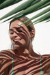 Young Woman with Shadow of Palm Leaves on White Wall