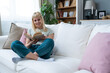 Simple living. Portrait of young beautiful blonde student or college girl sitting at home on sofa enjoying her life, free time and new apartment that she rented and moved in to live alone in quiet.