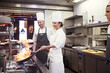 Restaurant, chef and pan with flame in kitchen for cooking, culinary career and hospitality service. Woman, hospitality and person in food industry with smile for fine dining, cuisine and preparation