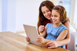 Mother, girl and tablet for bonding at table, online play and remote learning or education in home. Daughter, mama and website for cartoon or games for development, love and support in childhood