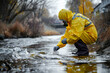 A worker in a yellow protective suit takes samples of polluted water - the concept of protecting the natural environment