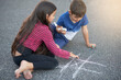 Chalk, road and kids with game, playing and outdoor in playground of preschool, summer and concentration. Creative, boy and girl in street, hopscotch and pavement for break in weekend and together