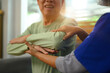 Smiling senior man exercising with his physiotherapist at home. Healthcare concept