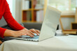 Close up young woman in red sweater hands typing on laptop keyboard
