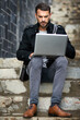 Man, typing and laptop on stairs for remote work, email, and research for writing. Creative, male person and copywriter with computer for freelance articles or blog outdoors in urban New York