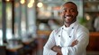 Portrait of a smiling black man chef, demonstrating confidence and years of experience in the highest cuisine in a restaurant.