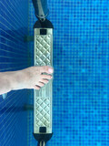 Fototapeta Tulipany - female foot step into swimming pool with ladder