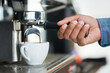 Espresso, barista and coffee machine in cafe for morning, beverage and hot liquid for brewing. Hand, waiter and working in restaurant for drink, cappuccino and breakfast in cafeteria or hotel