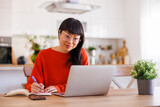 Fototapeta Koty - Mature woman taking online course at home using laptop computer