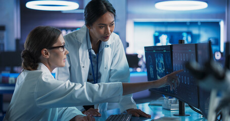 Poster - Asian And Caucasian Female Doctors Talking In Medical Research Center And Using Desktop Computer To Analyze MRI Scans Of Brain. Surgeon And Neuroscientist Discussing Solutions For Treating Cancer.