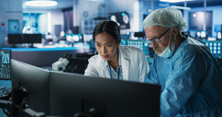 Poster - Medical Hospital Research Lab Meeting: Female Asian Neuroscientist Talking To Male Caucasian Neurosurgeon About CT Brain Scans On Desktop Computer. Man Wearing Surgical Gown, Preparing For Surgery.
