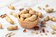 Roasted peanuts with shell in wood bowl on white marble table