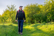 A man walks along a path among trees and green grass