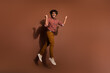© deagreez - Full size photo of nice young man jump raise fists luck wear striped shirt isolated on brown color background