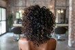 © SOLDATOOFF - Back view of a beautiful young African American woman with curly hair in a beauty parlor.