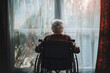 Senile depression Concept. Melancholic mood Lonely and sad elderly person in wheelchair in nursing home looking out window.