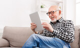 Fototapeta  - Senior man reading news on digital tablet
