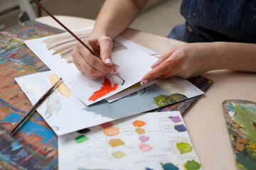 Young female artist paints a picture with oil on canvas in art studio