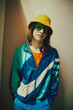 Young boy wearing colorful, retro-inspired windbreaker, paired with sleek sunglasses and yellow panama, Urban sport fashion. Concept of 90s, fashion, youth culture, old-style trends