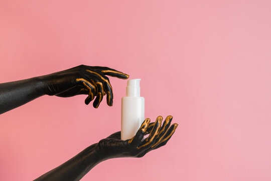Cosmetic glass tube in hands with black paint on her skin. Presenting luxury skincare products. Image for your design