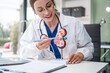 © NanSan - Caucasian woman sits at a desk, kidney model, gallstones, glomerulonephritis, acute and chronic kidney disease, infectious diseases, abnormal ureters, cysts, and urinary system cancer.