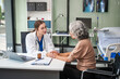 © NanSan - Caucasian female psychiatrist sits at her desk, providing mental health consultations and therapy sessions to her patients with empathy and expertise. elderly patient sit on wheelchair.