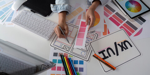Wall Mural - stylish woman ux designer using digital tablet and computer planning new website wireframe at creati