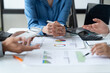 © Tj - close-up hands image, Professional Asian male and female financial consultant or analyst working with them team, brainstorming and analyzing financial data on the report together in the office