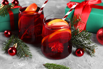 Wall Mural - Delicious Sangria drink in glasses and Christmas decorations on grey textured table, closeup