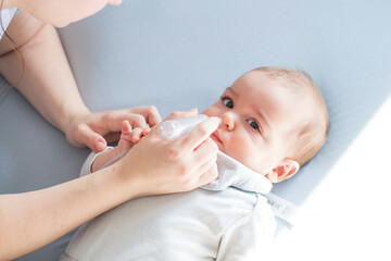 mother using baby nasal aspirator mucus nose suction. mother cleaning baby nose. baby watching to ca