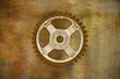 Old weathered gear wheel on a brass background