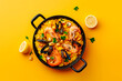 Traditional spanish seafood paella on yellow background. Top view. Copy space