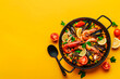 Traditional spanish seafood paella on yellow background. Top view. Copy space
