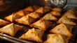 Close-up of a tray of baked samosas being pulled out of the oven, showcasing the golden crust and fragrant aroma of these healthier versions of the classic snack.