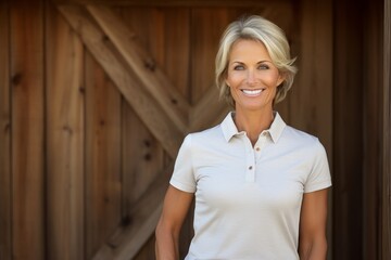 Wall Mural - Portrait of a cheerful woman in her 40s wearing a breathable golf polo over rustic wooden wall