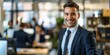 © LukaszDesign - Confident young Caucasian businessman smiling in workplace with colleagues. Dedicated entrepreneur and leader willing to succeed in startup with team