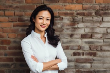 Wall Mural - Portrait of a glad asian woman in her 40s wearing a classic white shirt while standing against vintage brick wall