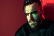 © LukaszDesign - Fashion, face, and contemporary man in studio with red background, green light, style, and elegance. Man model, handsome portrait, young or edgy, creative or stylish.