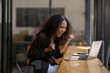 © Wasana - Joyful African American businesswoman celebrating a successful moment while using her laptop in a bustling café.