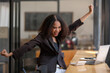 © Wasana - Ecstatic African American businesswoman celebrating a work victory while seated at her laptop in a café.