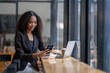 © Wasana - Cheerful African American businesswoman having a phone conversation while working on a laptop in a modern office.