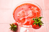 Fototapeta  - Strawberry margarita with tequila, ice, strawberry and lime at pink background. Close up.