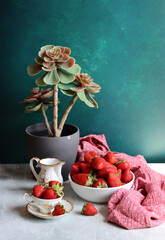 Sticker - Strawberries in cups and vase with succulent on green table. Dark background with copy space. Still life with ripe summer berries. Balanced diet concept. 