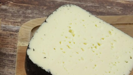 Wall Mural - tranche de fromage : tomme noire des Pyrénées, en gros plan, sur une table