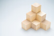 Stack of wood cubes built as step stairs pyramid on white background, wooden toy, permanent, and strong success