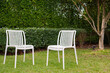 Two plastic white chairs in the garden backyard, garden ladder back chairs outside the house