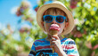 ©  ArtificialMango - Little boy in blue sunglasses and summer hat eating strawberry ice cream cone