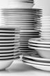 Towers of empty white plates, on a white table, black and white photography